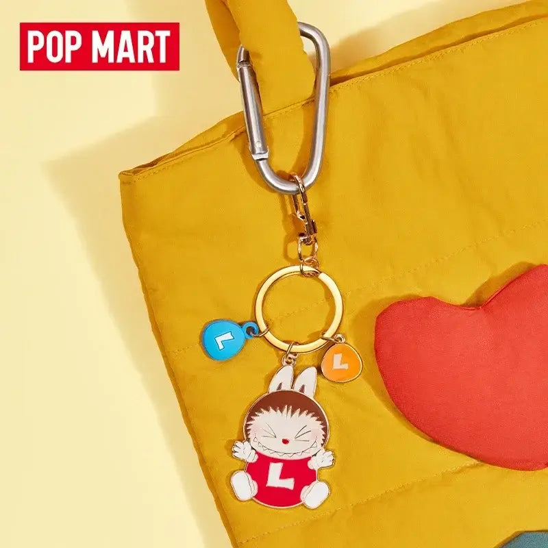 Labubu Porte-Clefs Bonbons accroché à un sac jaune avec un décor coloré de Pop Mart.