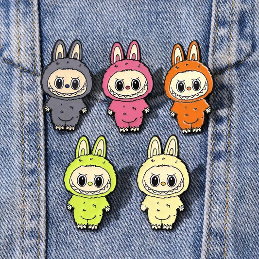 alt="Pins Labubu métal collection rare – 9 modèles colorés sur fond vert, broches pour vestes, sacs et accessoires"